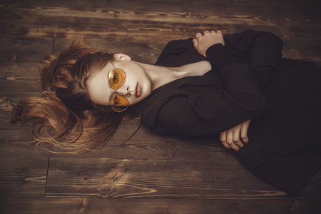 A portrait of a thoughtful young woman posing on the floor. Beauty, fashion, optics.の写真素材