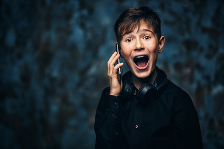 A portrait of a young boy with a smartphone and headphones. Fashion, gadgets.の写真素材