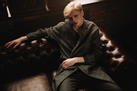 Portrait of a sexy handsome man on a leather sofa. Fashion shot. Men's beauty, fashion.の写真素材