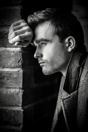 A close up portrait of a thoughtful fashionable young man near the brick wall. Casual fashion for men.の写真素材