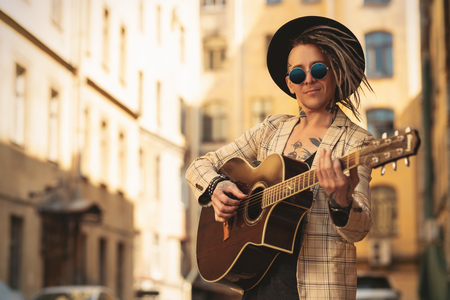 A portrait of a young guitarist in the street. Casual summer fashion, music.の写真素材