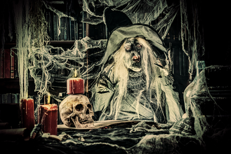 A scary witch is reading a book of spells. The Concept Of Halloween. Horror movie.の写真素材