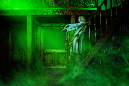 A full length portrait of a scary pale girl from a horror film in a room on the stairs. Zombie, halloween.の写真素材