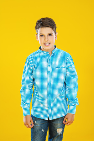 A portrait of a cheerful young boy over the yellow background. Beauty, summer, fashion.の写真素材