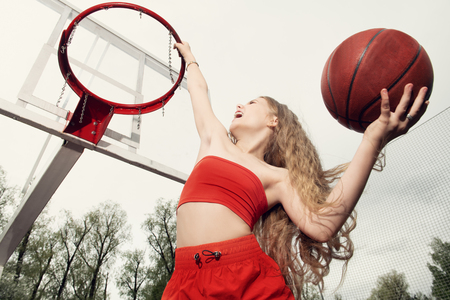 A portrait of a sporty teenager girl posing on the basketball pinch. Sport fashion, active lifestyle, basketball.の写真素材