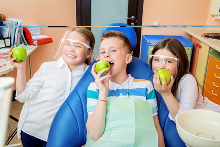 A portrait of three happy children in the cabinet of a dentist. treatment, medicine, hospital.の写真素材