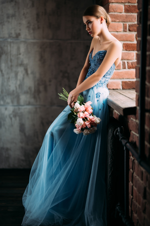 A portrait of a mysterious lady in a fluffy dress posing indoor with flowers. Fairy tale, fashion.の写真素材