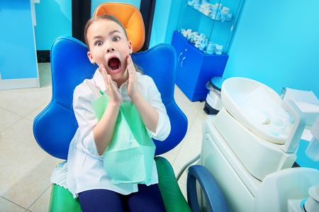 A portrait of a frightened child girl in the cabinet of a dentist. treatment, medicine, hospital.の写真素材