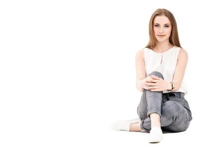 A portrait of a beautiful dark-haired girl sitting in the studio over the white background. Beauty, formal fashion.の写真素材