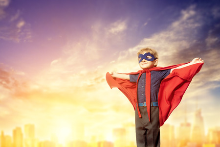 A full length portrait of a funny smiling young boy posing in the costume of superhero. Kids development and education concept.の写真素材
