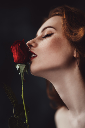 A close up portrait of a lovely mysterious girl with a red rose. Beauty, cosmetics.の写真素材