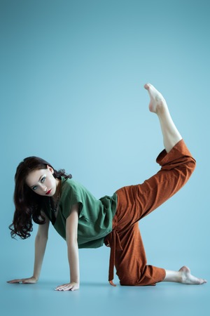 A full length portrait of a beautiful young woman dancing over the grey background in the studio. Casual fashion, fitness, yoga.の写真素材