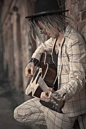 A portrait of a young guitarist in the street. Casual summer fashion, music.の写真素材