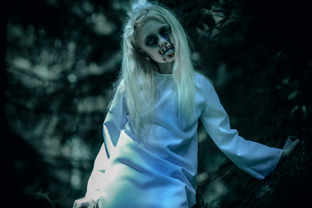 A portrait of a scary pale girl from a horror film in the forest. Zombie, halloween.の写真素材