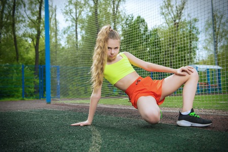 A full length portrait of a teenager girl posing on the sports ground. Sport fashion, active lifestyle.の写真素材