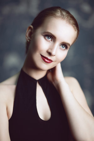 A portrait of a young lady posing over the grunge background in the studio. Style, beauty, fashion.