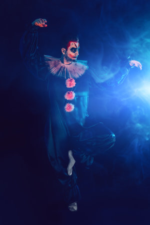 A full length portrait of a clown from a horror film. Halloween, carnival.