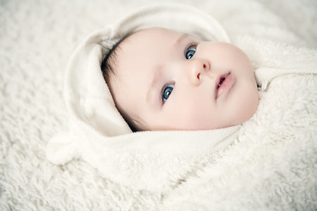 A portrait of a beautiful baby lying in the bed. Family, parenthood. Goods for newborns.