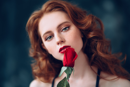 A close up portrait of a lovely mysterious girl with a red rose. Beauty, cosmetics.の写真素材