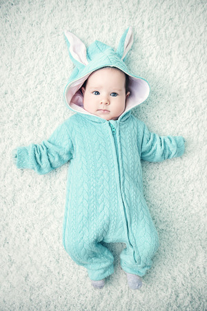 A portrait of a funny baby wearing a jumsuit of a hare. Family, parenthood. Goods for newborns.の写真素材