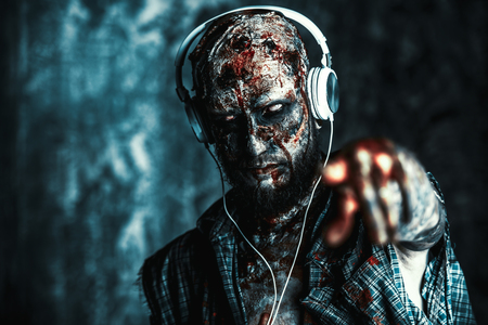 Creepy scary zombie is listening to music with headphones. Halloween. Horror film.の写真素材