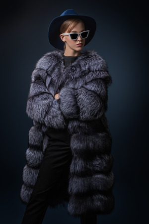 A portrait of a young fashionable woman in a hood and sunglasses. Beauty, optics, fashion.の写真素材