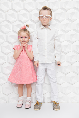 A full length portrait of two cute children posing in the studio over the white background. Kids, summer fashion, casual style.の写真素材