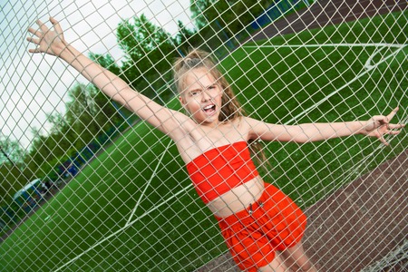 A portrait of a sporty teenager girl posing on the sports ground. Sport fashion, active lifestyle.の写真素材