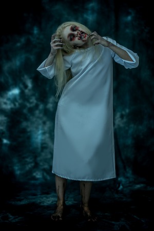 A full length portrait of a scary pale girl from a horror film. Zombie, halloween.の写真素材