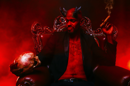 A portrait of a bad demon in his throne with a skull and cigar. Horror movie, nightmare. Halloween.の写真素材