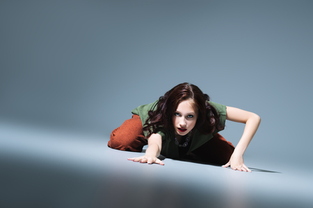 A full length portrait of a beautiful young woman dancing over the grey background in the studio. Casual fashion, fitness, yoga.の写真素材