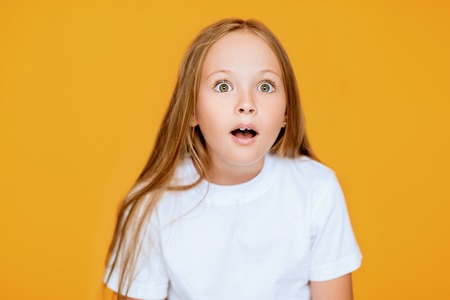 A portrait of a funny young pretty emotional surprised girl. Kids summer casual fashion, beauty, emotions.の写真素材