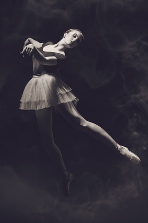 A full length portrait of an elegant refined ballet female dancer posing in the studio over the black background. Talent, fashion for ballet dancers.の写真素材