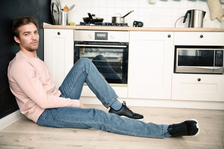 A full length portrait of a handsome man in the kitchen. Spring, autumn fashion for men, interior.の写真素材