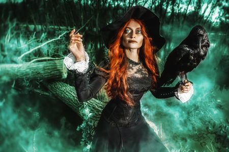 A portrait of an angry witch with a black raven outdoor. Magic, dark force, spell.の写真素材