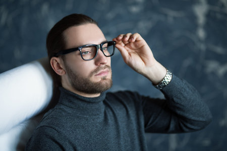 A portrait of a handsome stylish man sitting on the armchair. Fashion for men, beauty. Interior.