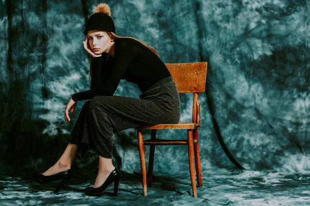 A full length portrait of a thoughtful fashionable young woman posing on the chair. Beauty, fashion.