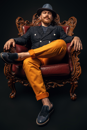 A full length portrait of a stylish modern man posing in the armchair. Men fashion, style.の写真素材