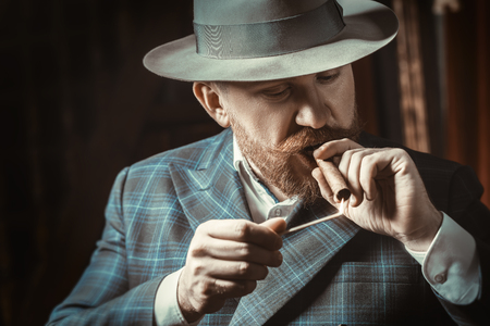 A close-up portrait of a thoughtful man with a cigar posing in the vintage interior. Men's beauty, fashion, style.の写真素材