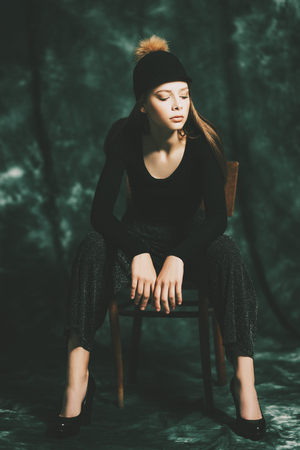 A full length portrait of a thoughtful fashionable young woman posing on the chair. Beauty, fashion.の写真素材