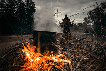A portrait of an angry witch near the fire cooking spell. Magic, dark force, spell.の写真素材