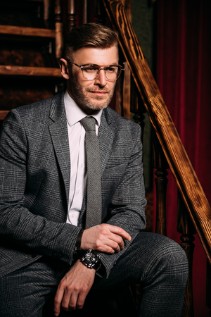 A portrait of a handsome mature man in a formal costume posing on the stairs. Men's beauty, fashion.の写真素材