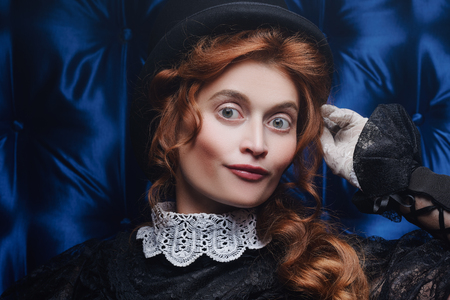 Close-up portrait of an elegant Victorian woman in black dress and top hat. Steampunk theme. The history of makeup and hairstyles.の写真素材