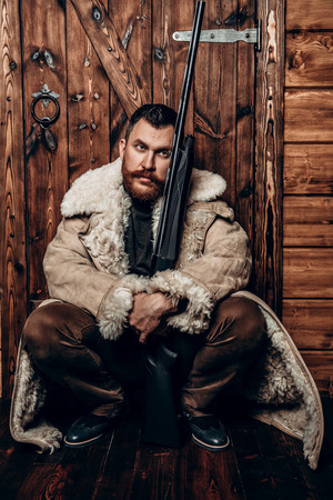 A portrait of a hunter man standing at the wooden house. Man, hunting, musket.の写真素材