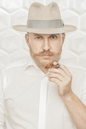 A portrait of a thoughtful man with a cigar posing in the studio over the white background. Men's beauty, fashion, style.の写真素材