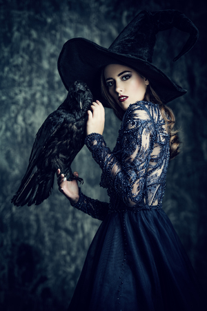 A witch in hat and dress with a raven. Halloween. Celebration.の写真素材