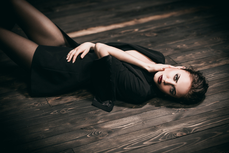 A portrait of a beautiful woman wearing a black blazer lying on the floor. Fashion, style, beauty.の写真素材