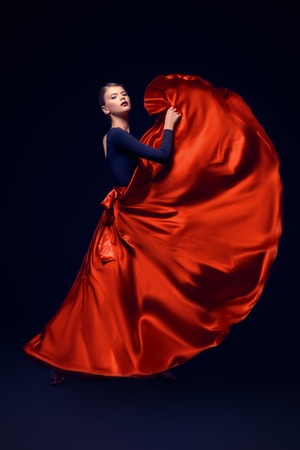 Beautiful girl professional dancer performs latino dance. Passion and expression. Black background.の写真素材