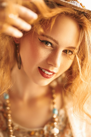 Portrait of a beautiful red-haired girl smiling at camera. Beauty and make-up concept. Hippie style. Bohemian style.の写真素材