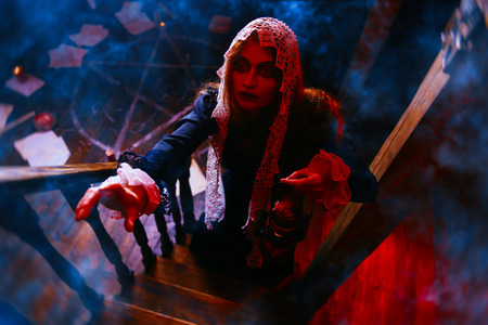 A portrait of a redhead witch with a lantern in her lair. Magic, dark force, spell.の写真素材